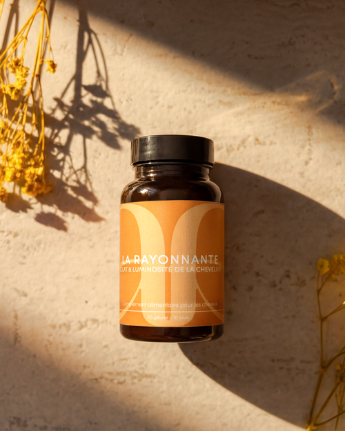 Présentation d'un complément alimentaire de la marque KAAMI qui s'appelle La Rayonnante. Elle a pour objectif d'améliorer l'éclat et la luminosité des cheveux. PAckaging jaune / orange avec fond neutre type marbre