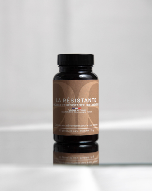 Packaging de La Résistante, flacon noir, étiquette marron. Pilulier placé sur une plaque en verre