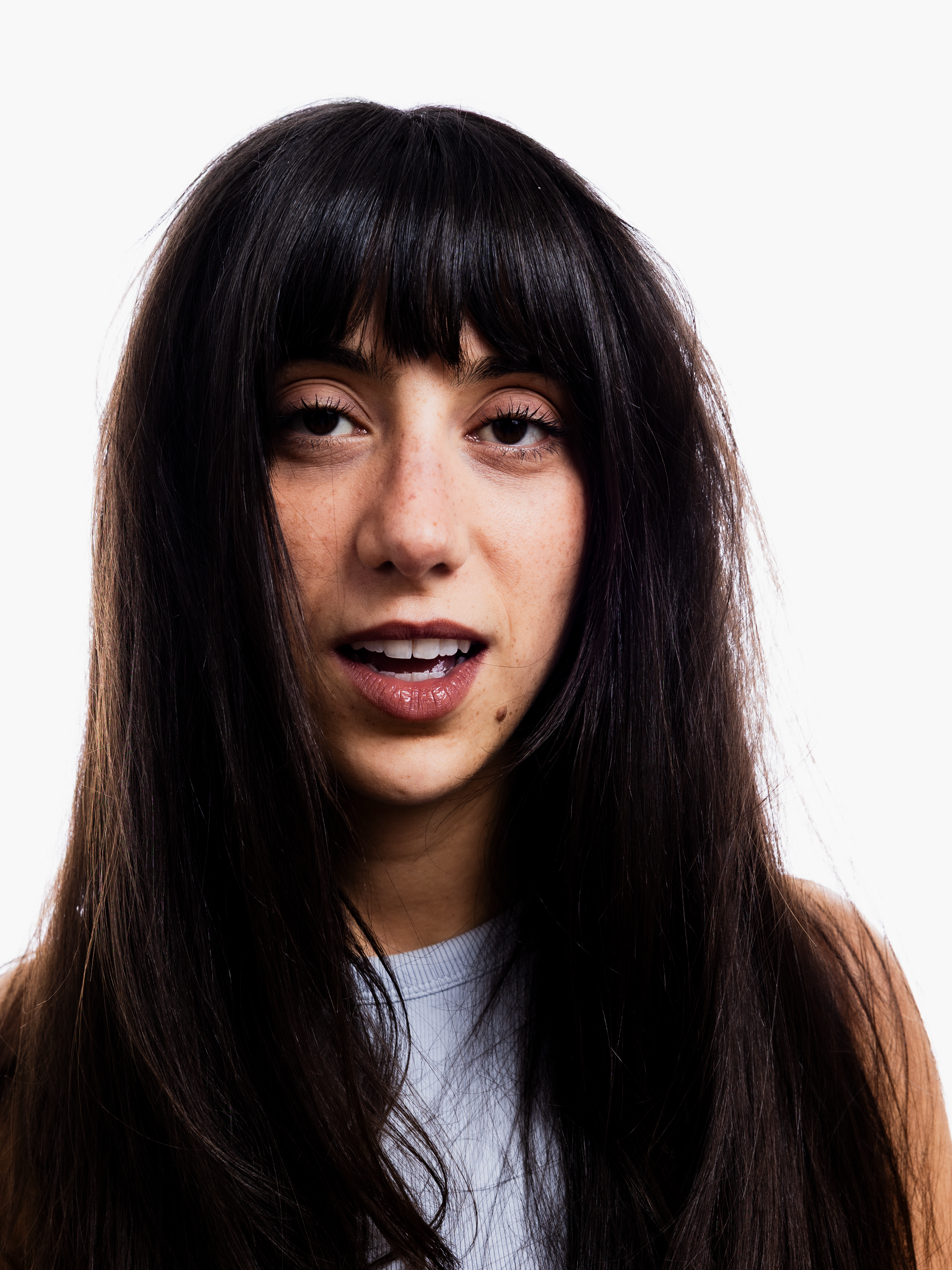 Photo de Pénéloppe, une jeune femme aux cheveux longs bruns prise de face. Elle a la bouche entre ouverte et le regarde fixe vers la caméra