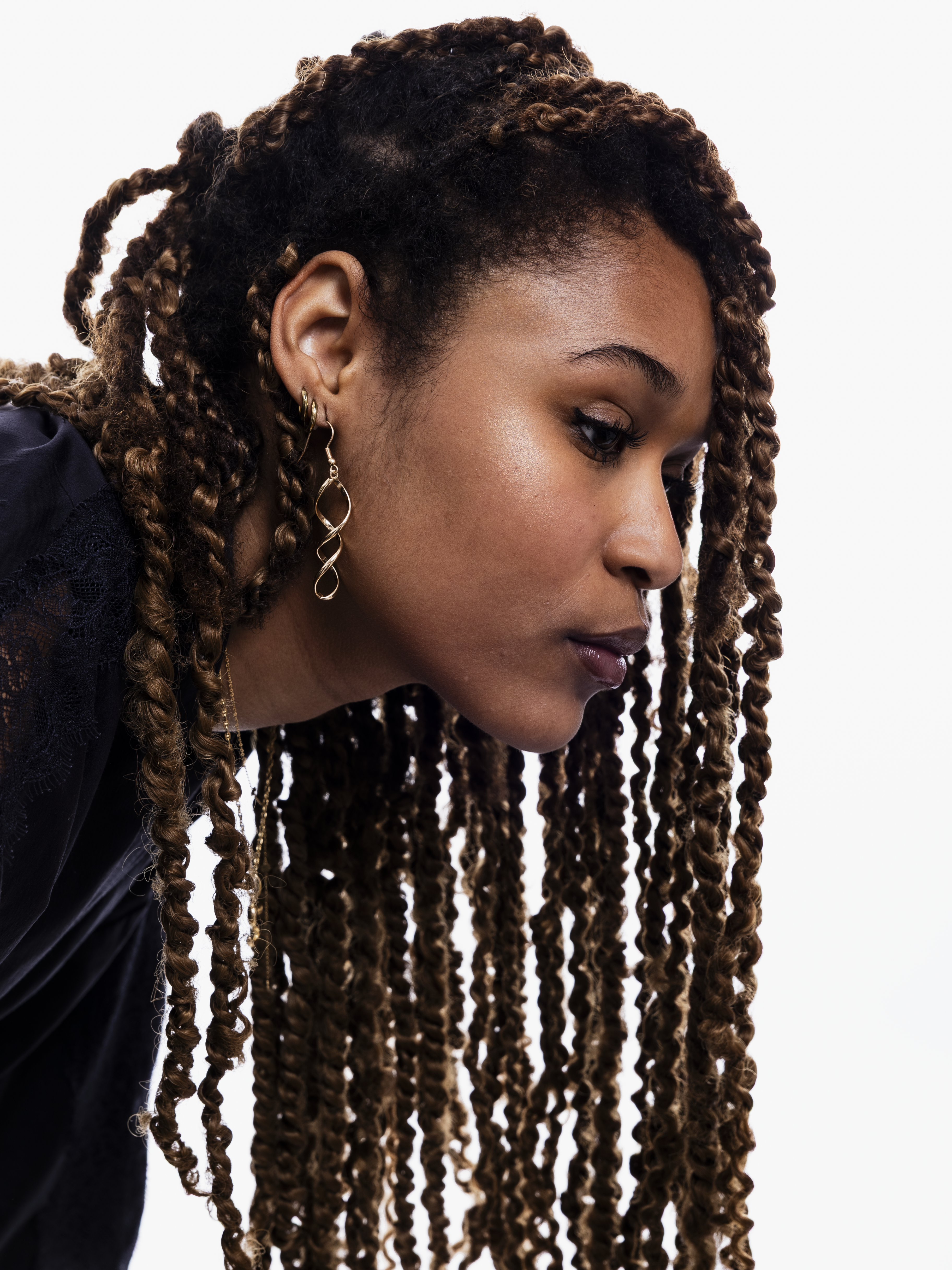 Photo de Salima, une jeune femme prise de profil Ses longues tresses tombent dans le vide. Son regard est porté vers le bas